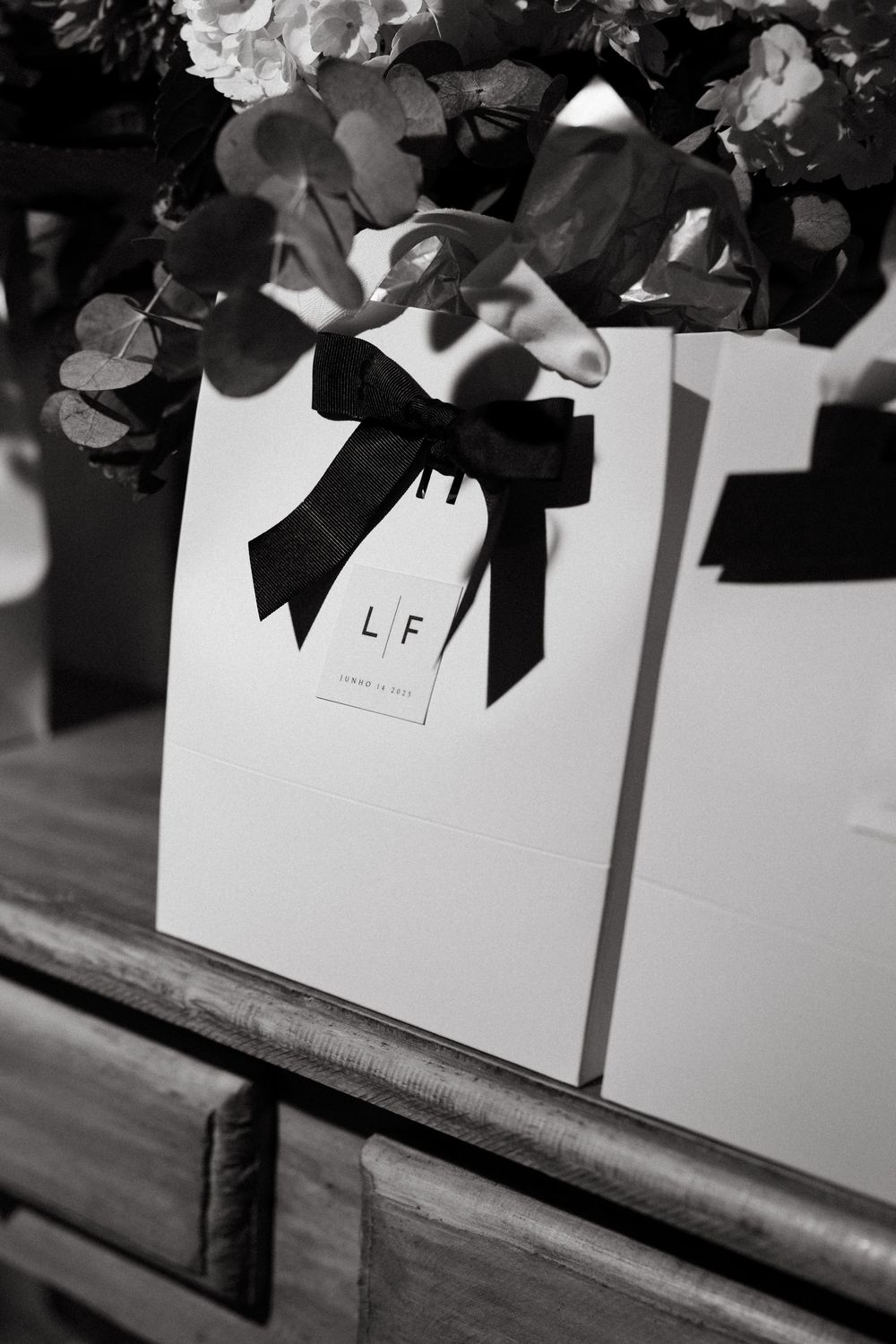 Black and white photo of white gift bags with black ribbon bows and LF monogram tags.