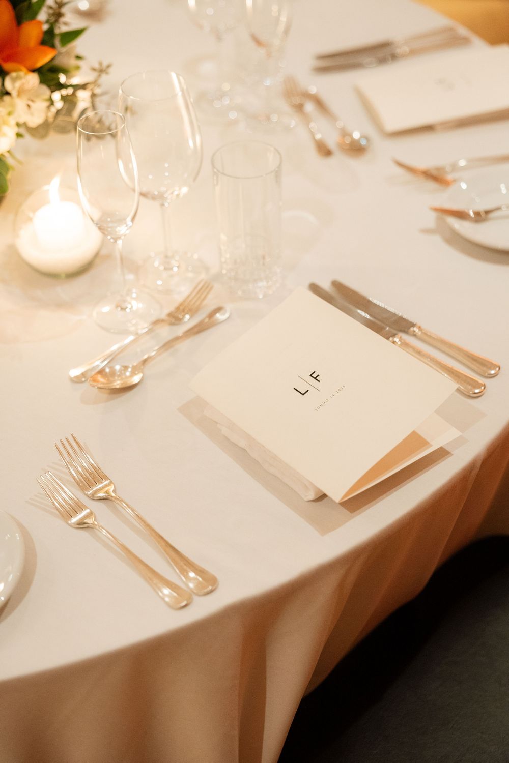 Elegant wedding table setting with LF monogram menu card, gold cutlery, and crystal glassware.