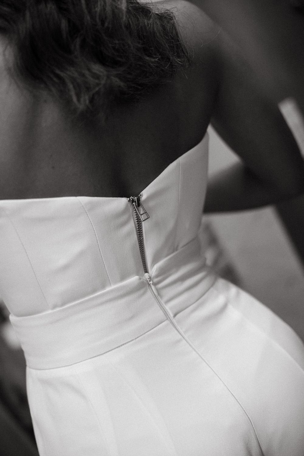 Back view of bride in strapless white wedding dress with zipper detail.
