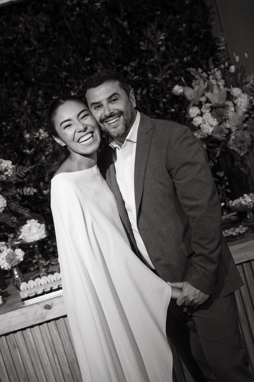 Joyful bride and groom laughing together in black and white wedding portrait.