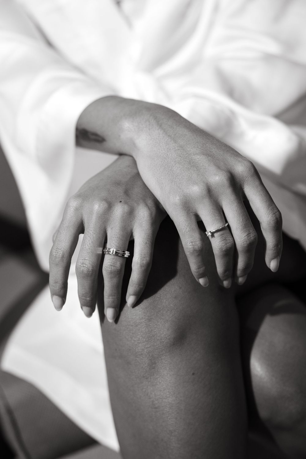 Close-up of bride's hands with engagement and wedding rings resting on knees.