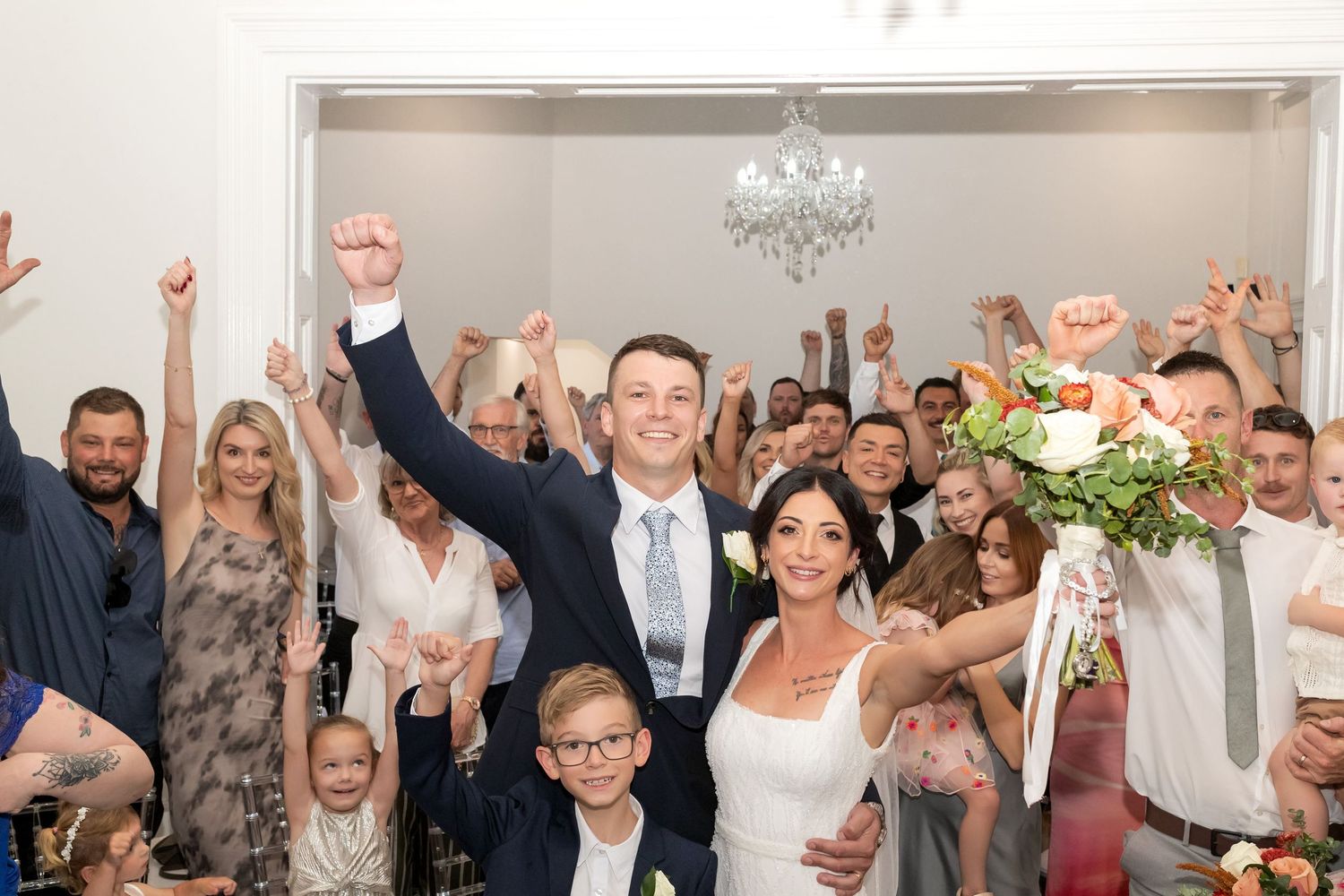 Bride and Groom celebrate with their whole wedding party in the background