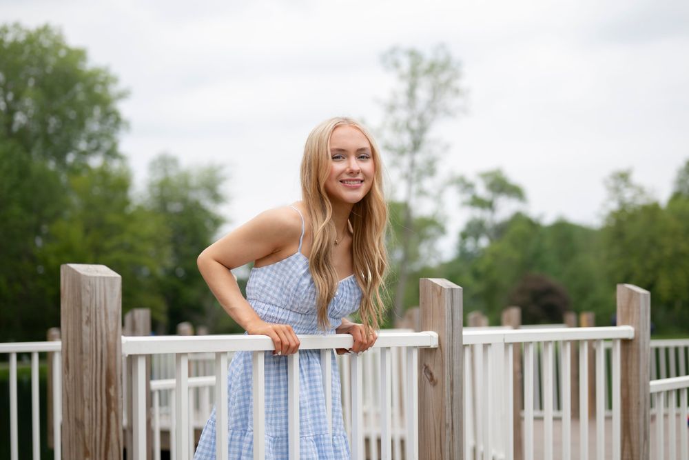 White railing of a wooden deck frames a summer scene by the water.