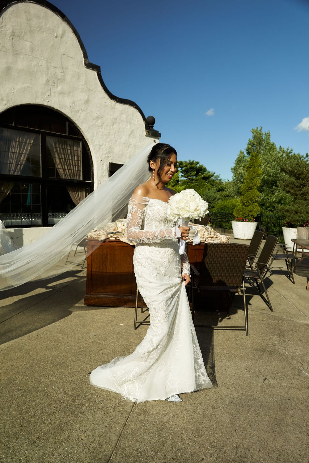 Elegant bridal gown with lace detailing twirls on outdoor terrace with architectural details.