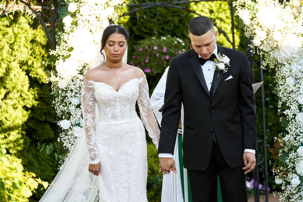 Wedding couple posing in garden setting with lush greenery and natural lighting.