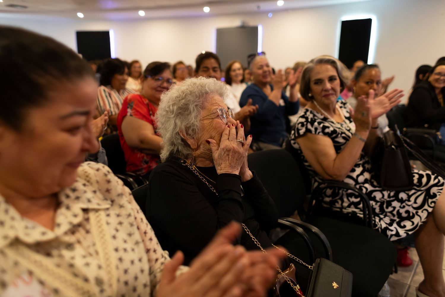 Crowd of people seated in rows at an indoor community event or gathering.