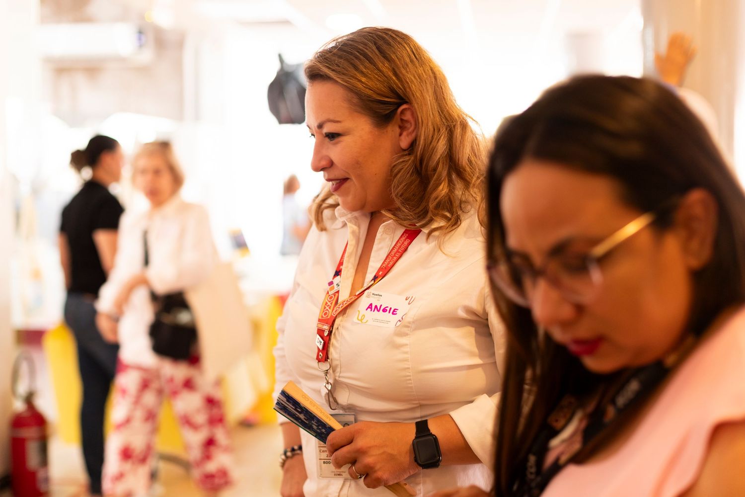 People interact at a casual indoor event with warm lighting and a friendly atmosphere.