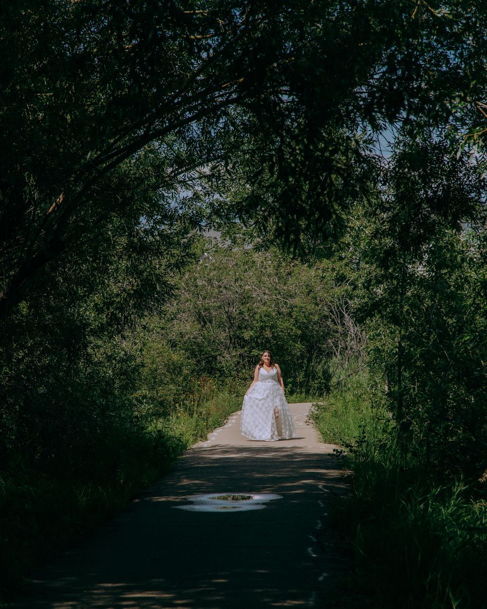 Wedding couple walking down a tree-lined path on their special day.