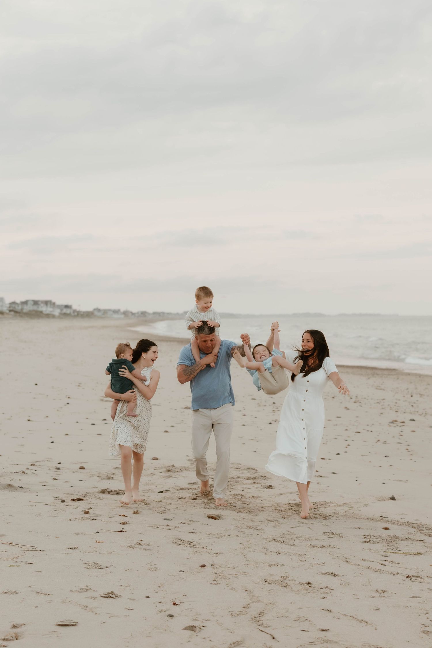 A joyful family plays together on a sandy beach at dusk.
