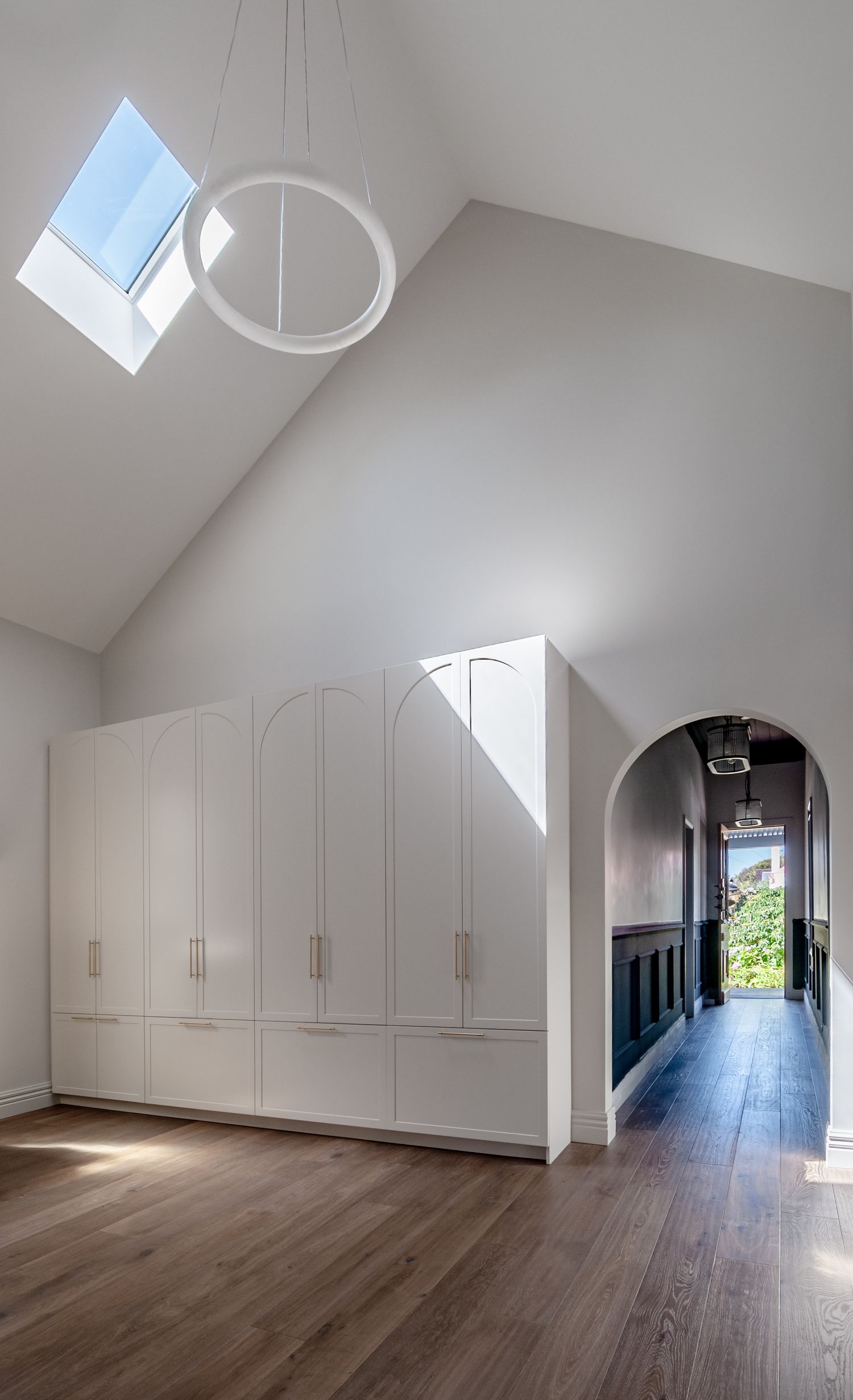 Bright hallway with white built-in storage cabinets and a skylight bringing natural light into the space.