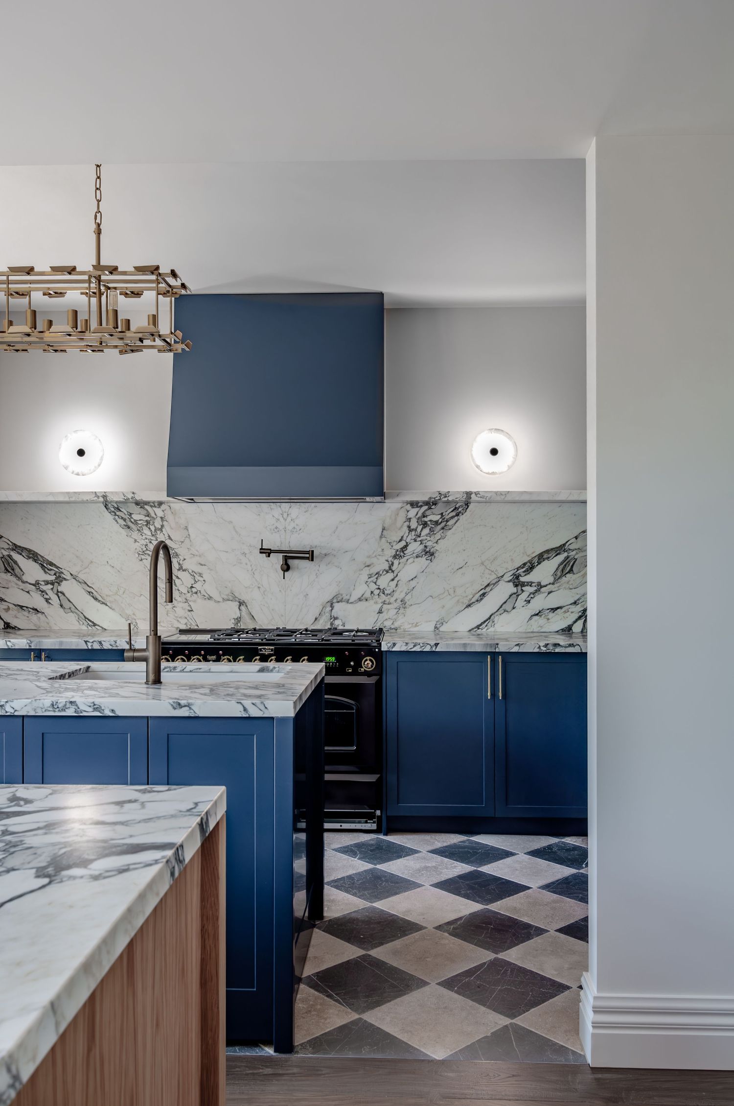 Elegant kitchen with navy blue cabinets, marble backsplash and geometric patterned floor.