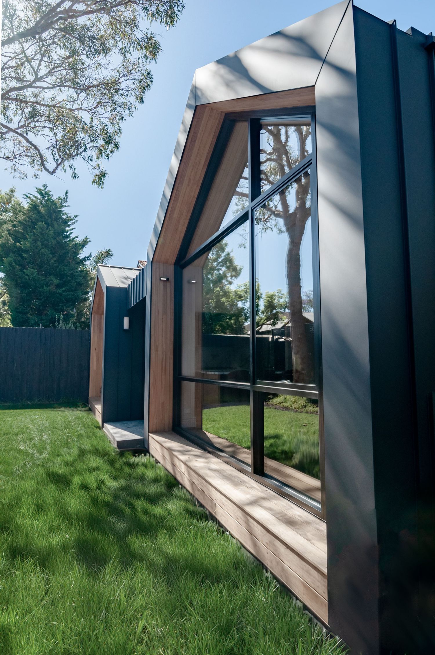 Angular black garden room with full-height windows and timber trim shown from a side perspective.