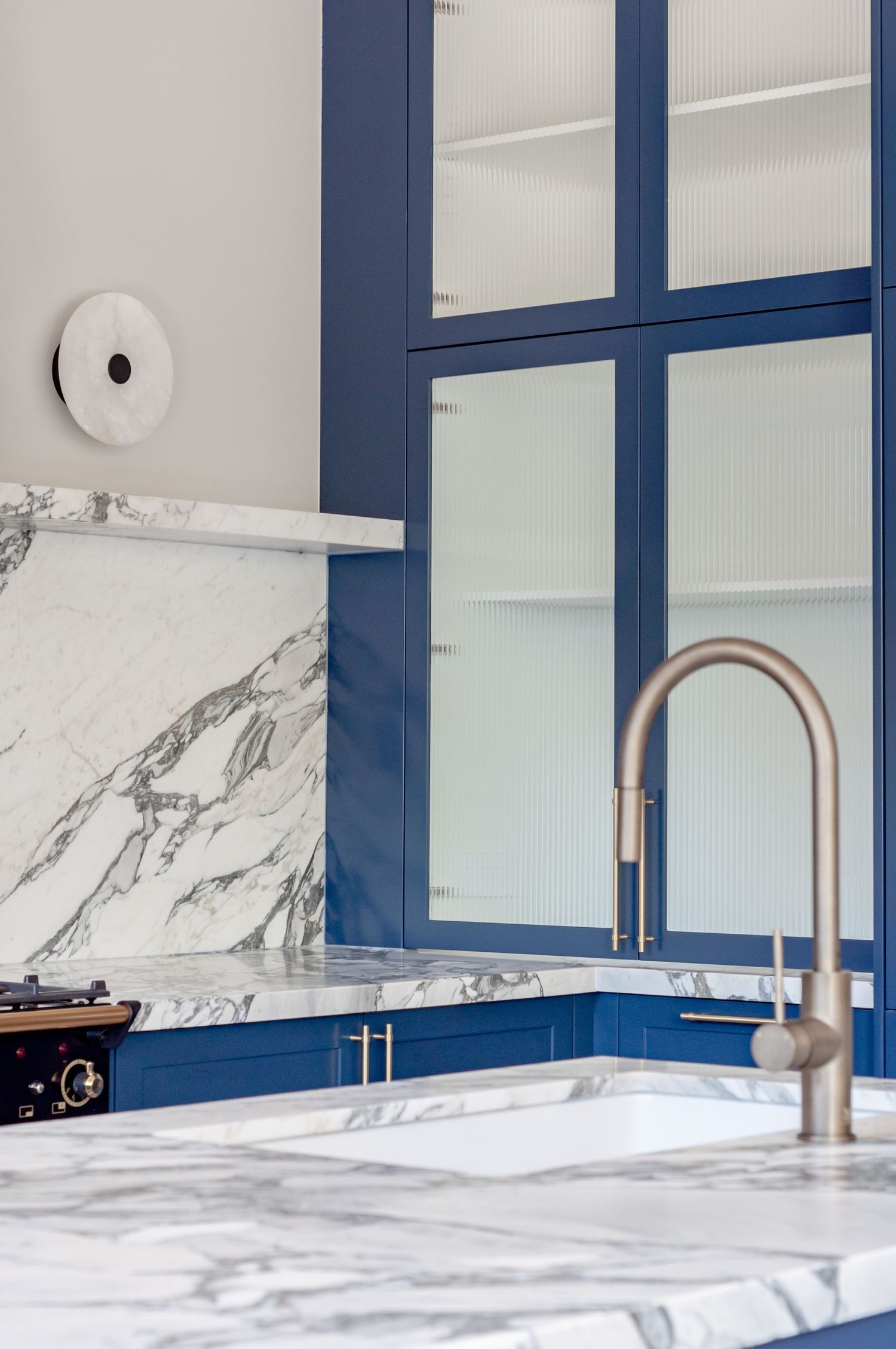 Navy blue framed cabinet with marble countertop and modern stainless steel faucet.