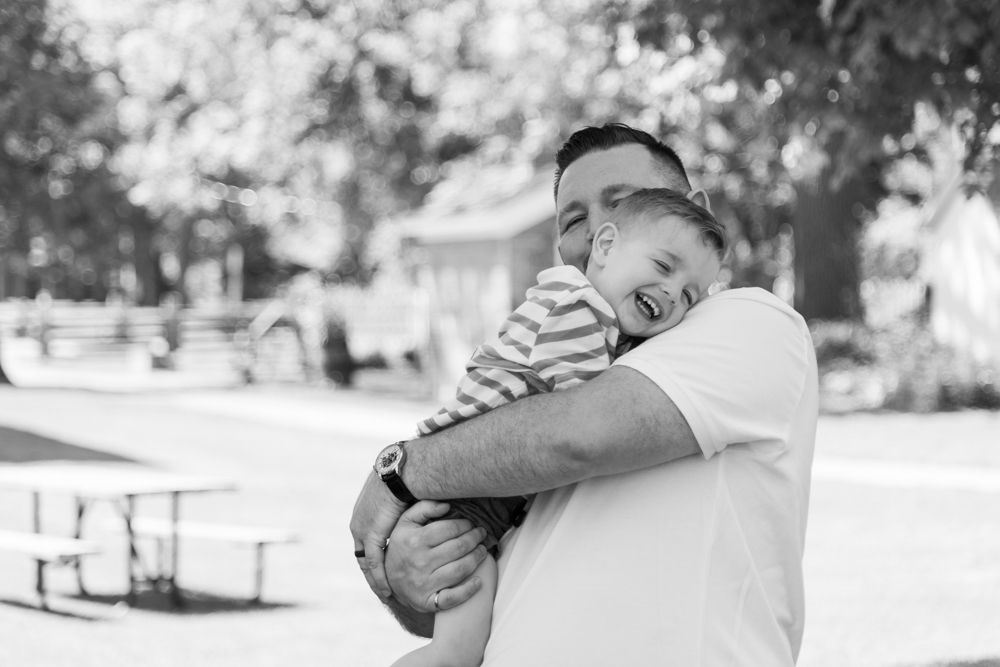 A joyful black and white moment of embrace captured outdoors in a park setting.