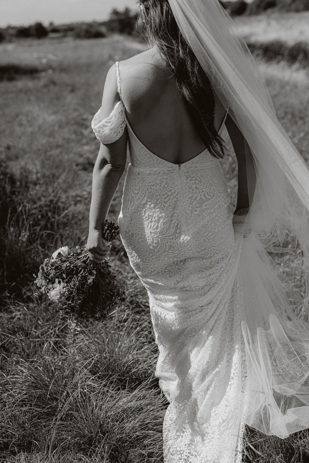 Close-up details of a lace wedding dress with flowing veil in black and white.