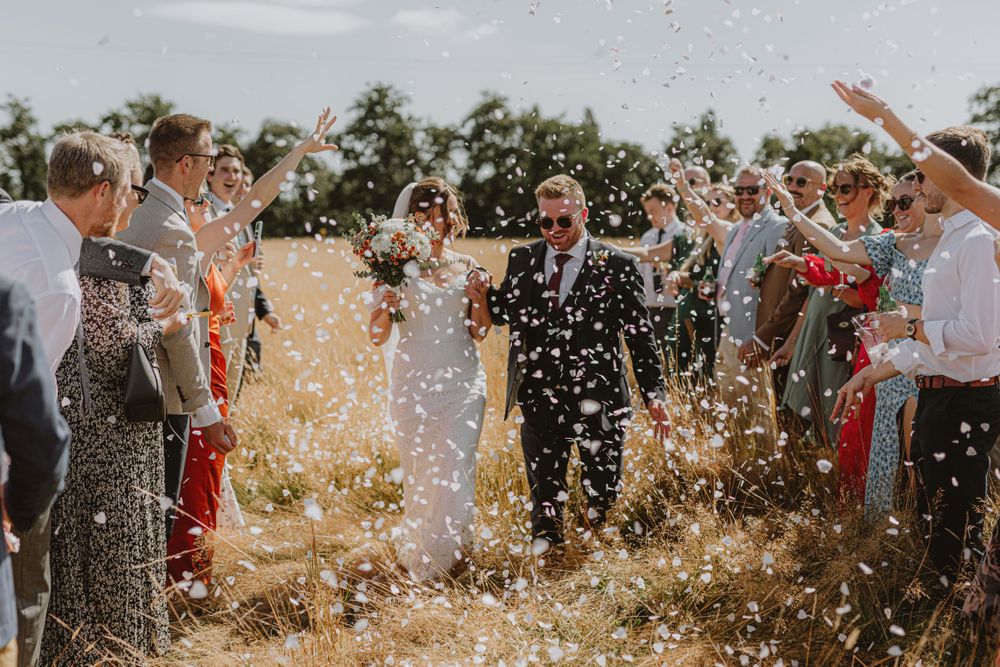 Wedding celebration with confetti being thrown in an outdoor setting.