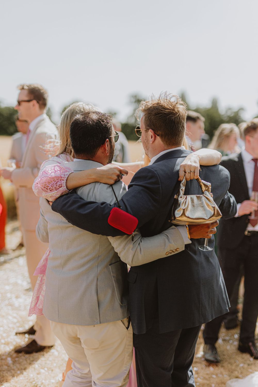 Wedding guests embracing in groups during an outdoor celebration.
