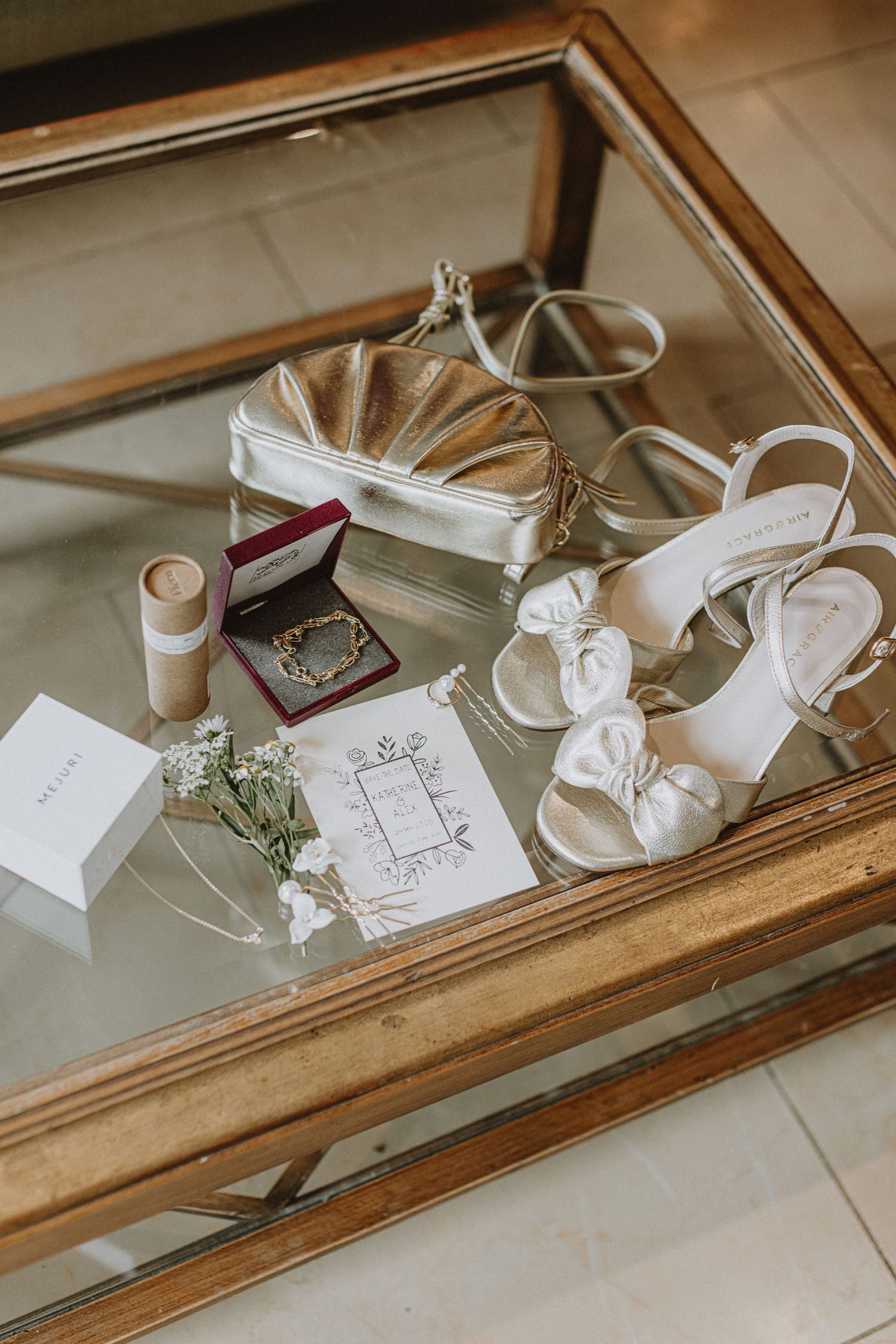 Wedding details flatlay with white shoes, invitations and accessories in vintage gold frame.