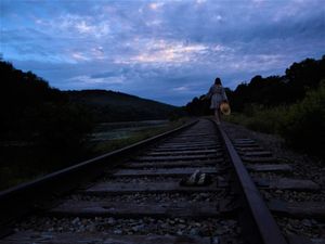 Railroad tracks extend into the distance under a dramatic cloudy sunset sky.