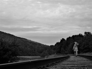 Black and white photograph of railroad tracks leading through a mountainous landscape.