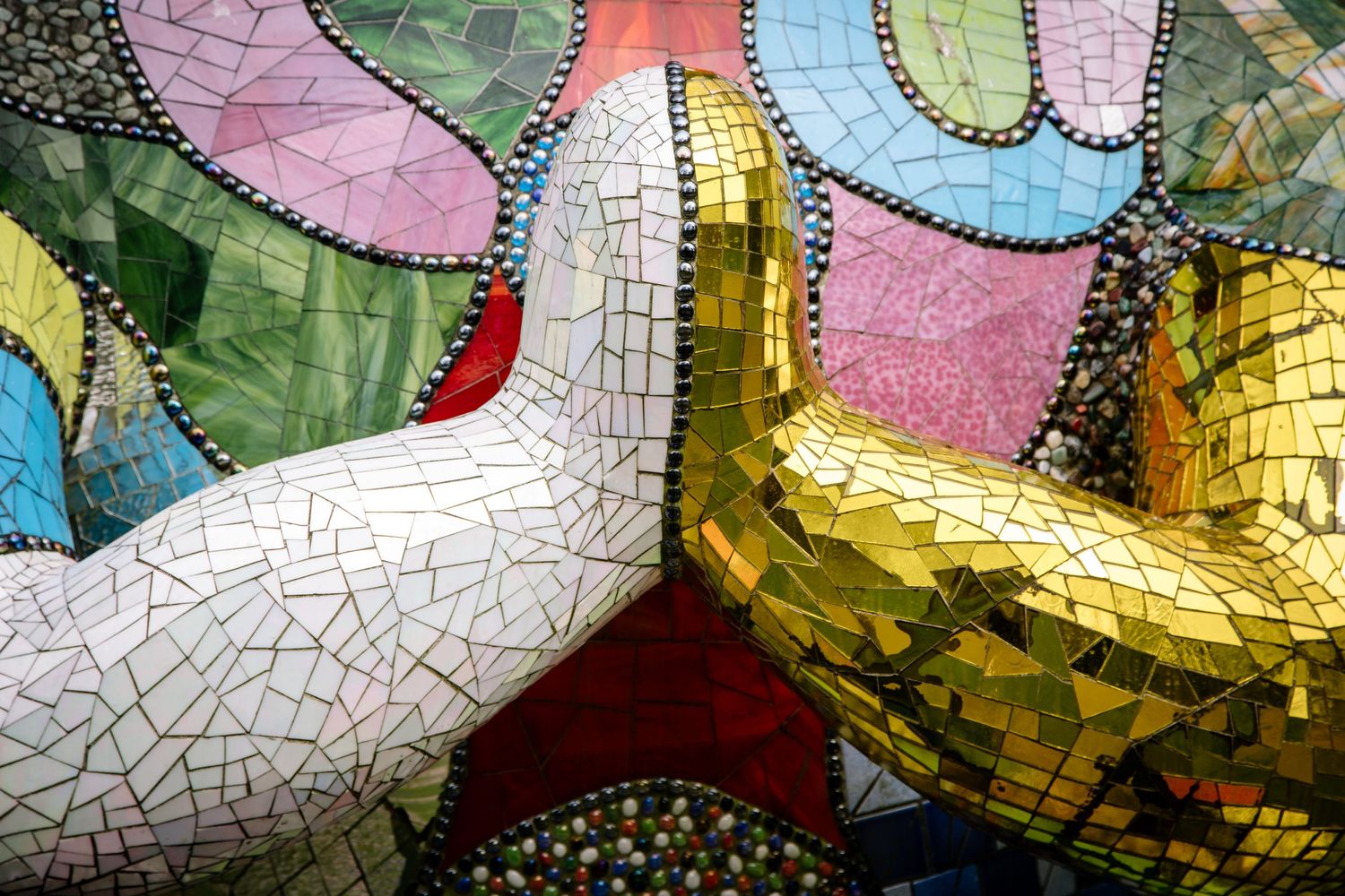 Colorful mosaic artwork featuring white and gold abstract designs with crackled textures.