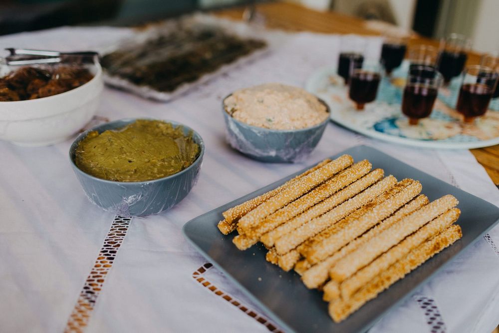 Appetizer spread with breadsticks and dips served on white tablecloth.