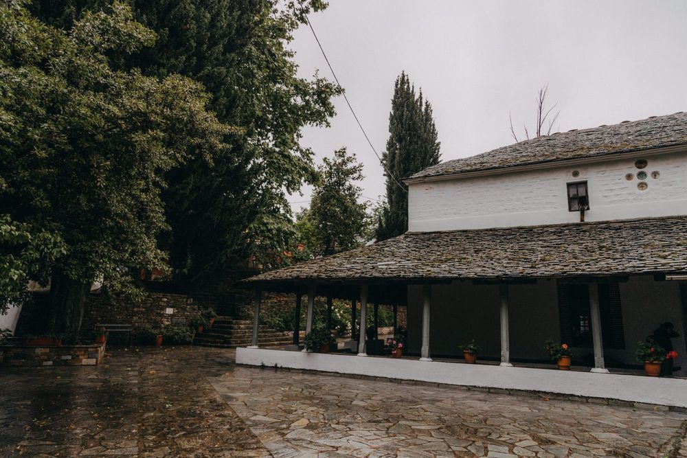 Traditional stone building with columned porch under overcast sky.