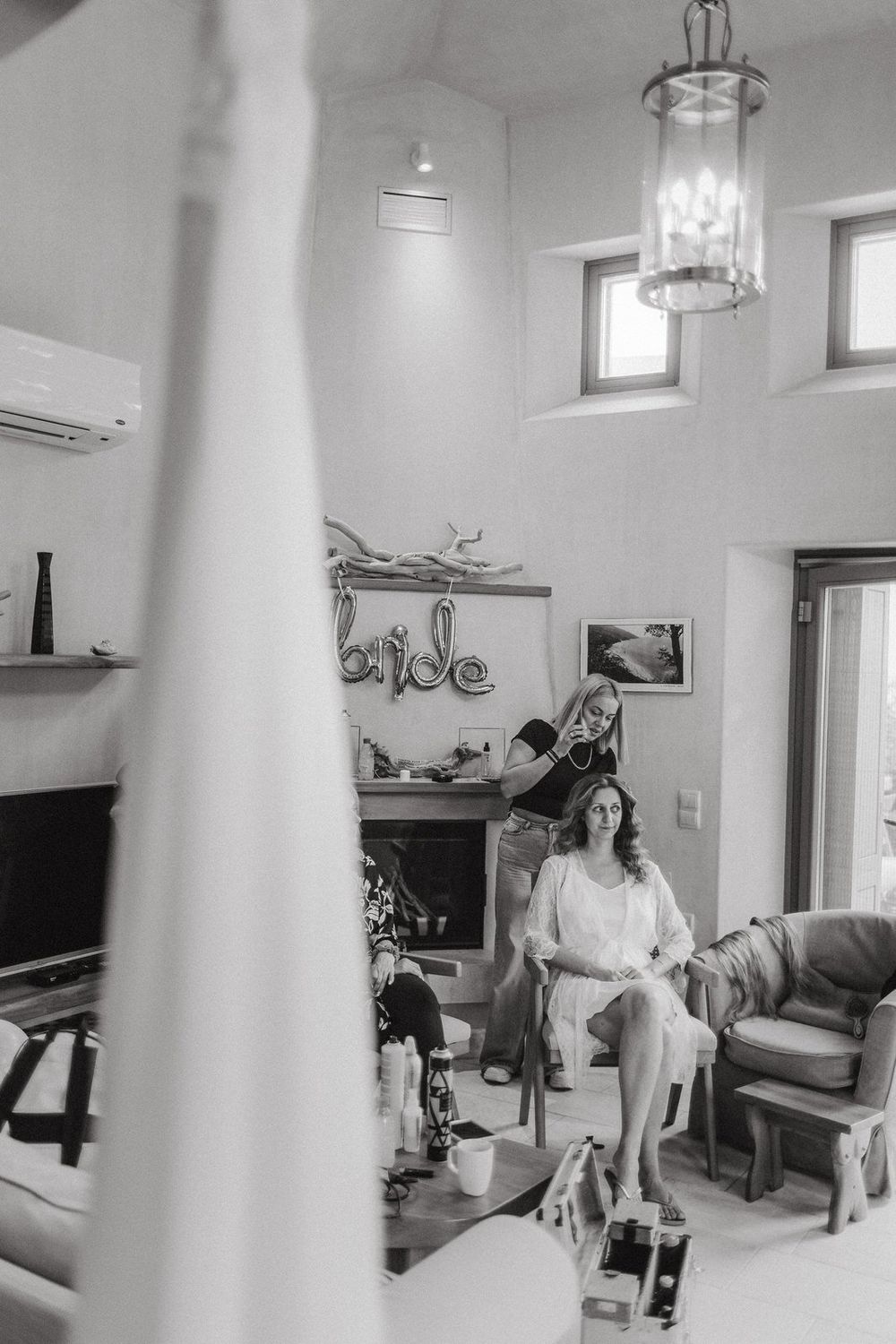Black and white interior photo of a living room with high windows and decorative lighting fixtures.