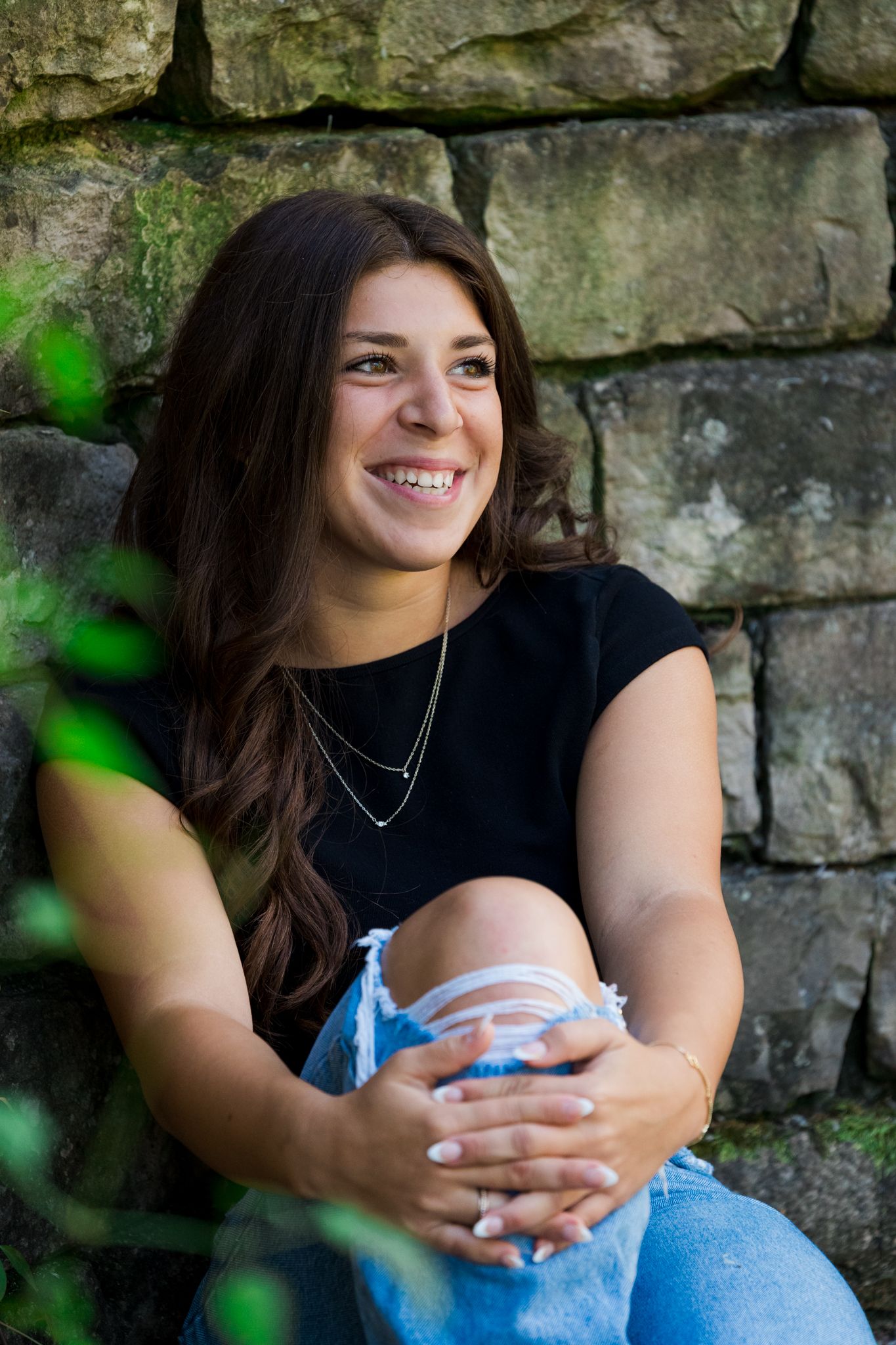 A series of outdoor portraits against a stone wall backdrop with natural greenery framing the composition.
