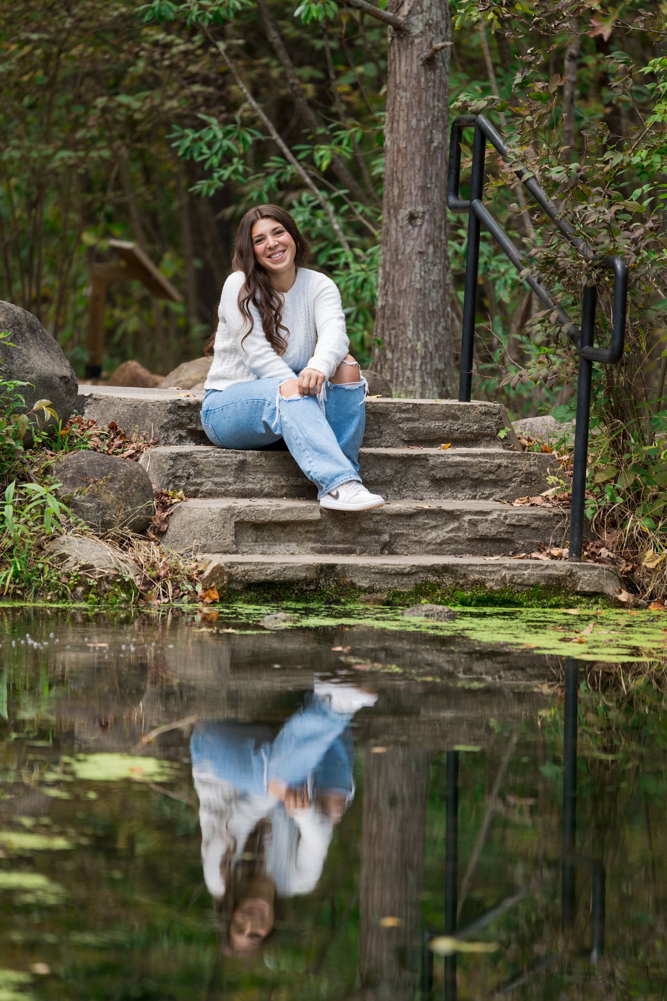 Reflective pond scene with stone steps and greenery creates a peaceful outdoor setting in nature.