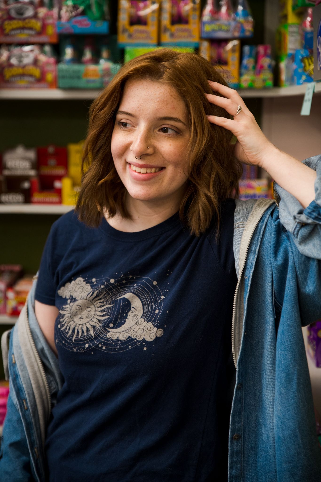 A smiling figure in a navy t-shirt with celestial moon artwork shops in a colorful retail store.