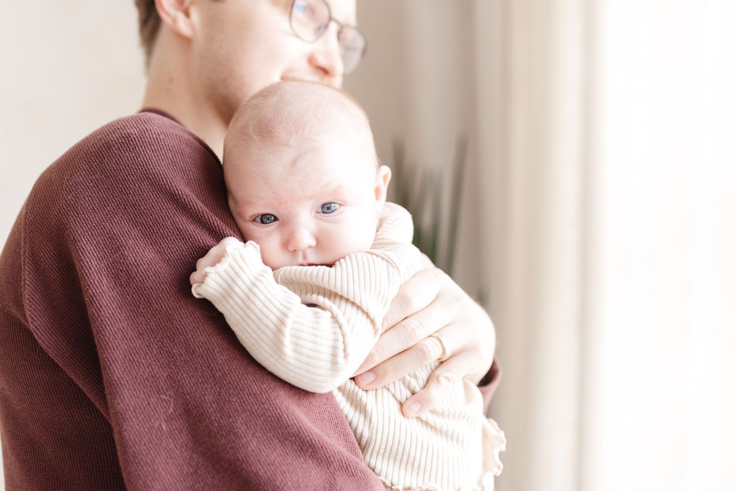 Father holding newborn baby in a bright and airy setting for a Toronto lifestyle newborn photoshoot