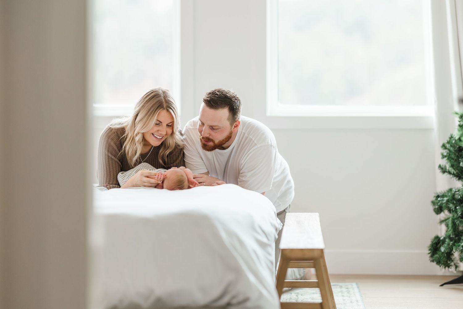 A couple embraces on a white couch in a bright, minimalist living room with natural lighting.