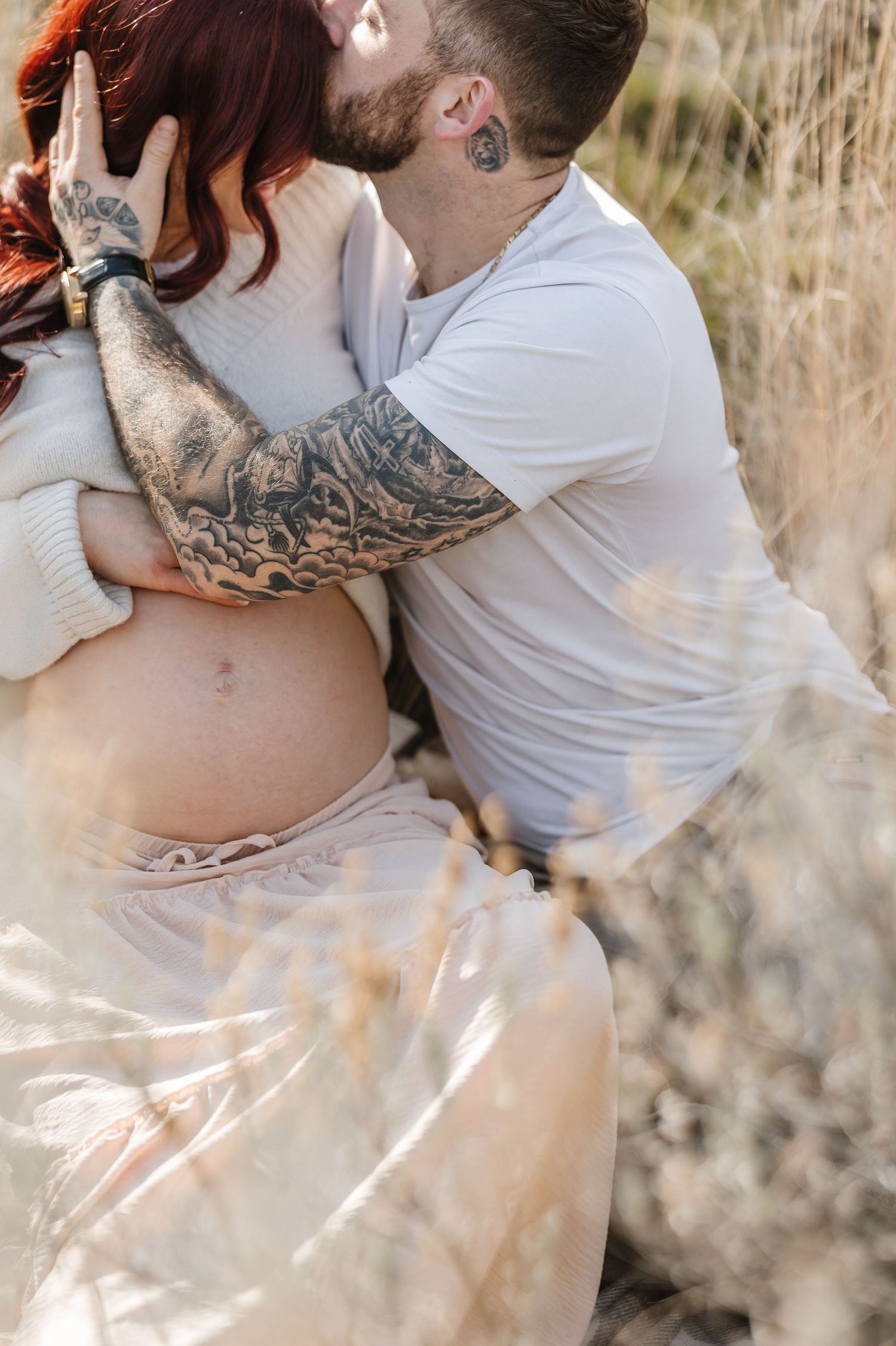 A couple embraces intimately in a sun-lit field of tall grass during a romantic outdoor photoshoot outdoors in Kelowna, BC