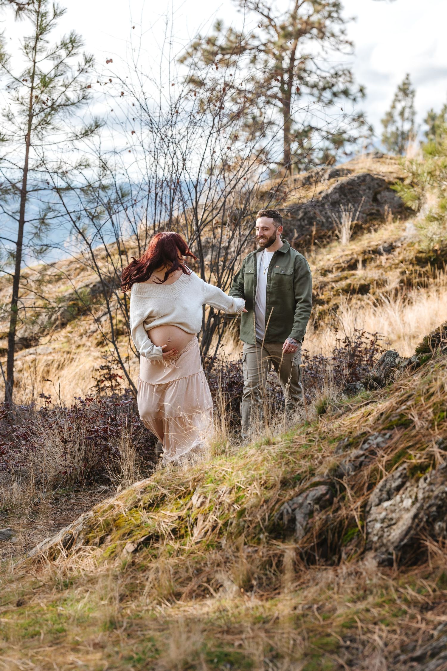A couple shares a romantic moment on a rocky hillside down a Knox mountain trail located in kelowna BC