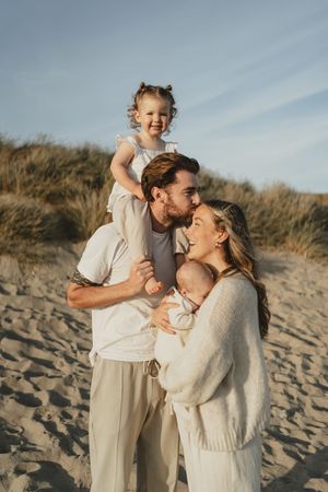 A family shares tender moments together on a sunny beach with white clothing.