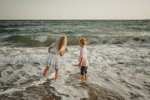 Children playing in ocean waves at the beach during golden hour.