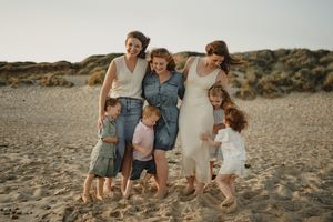 Extended family gathering on coastal rocks during sunset wearing coordinated outfits.