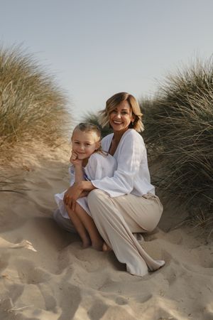 Intimate family moment captured in sand dunes with beach grass at sunset.