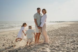 Family enjoying time together on sandy beach during golden hour.