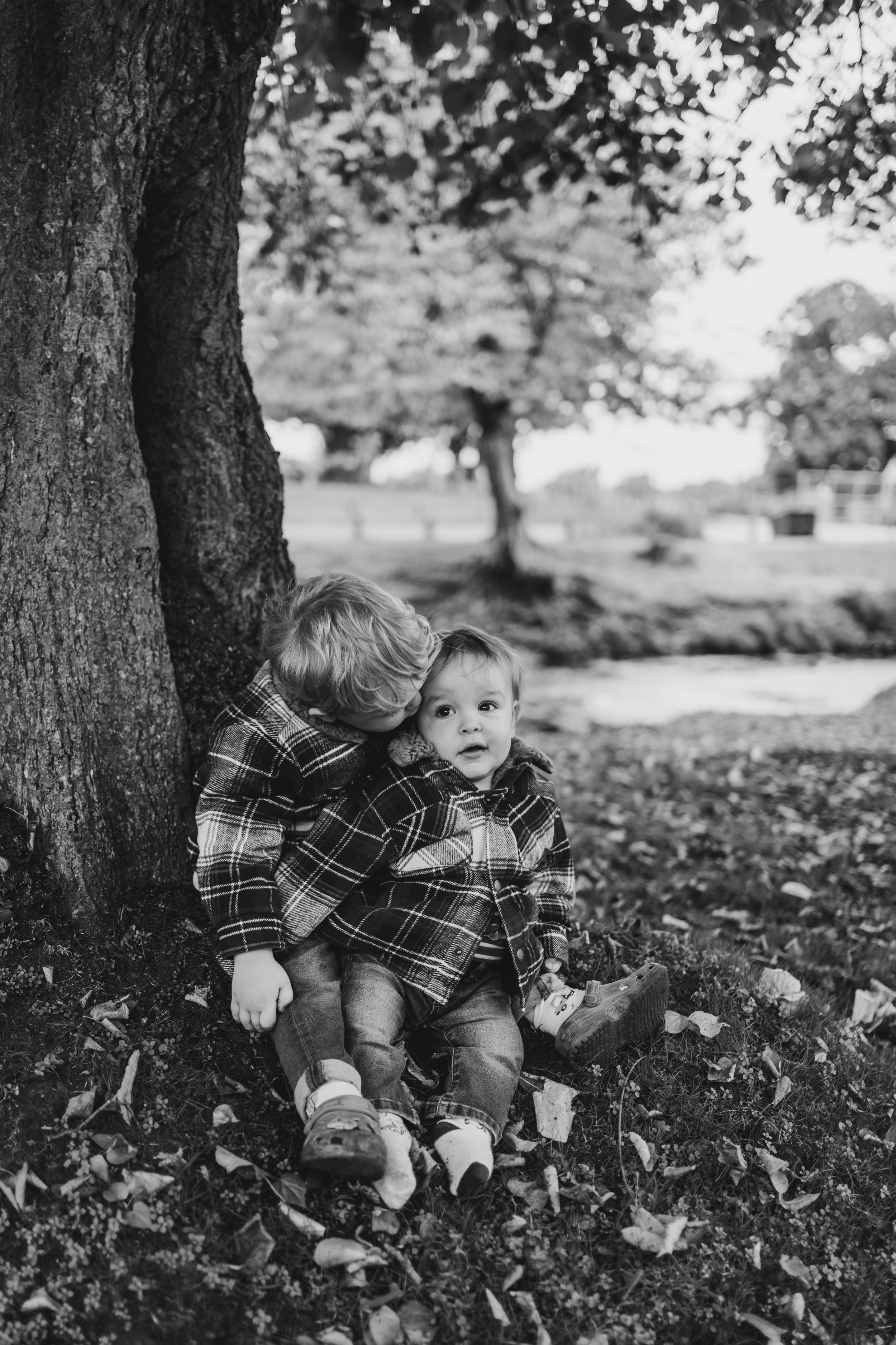 Black and white photo of small child playing in fallen autumn leaves.