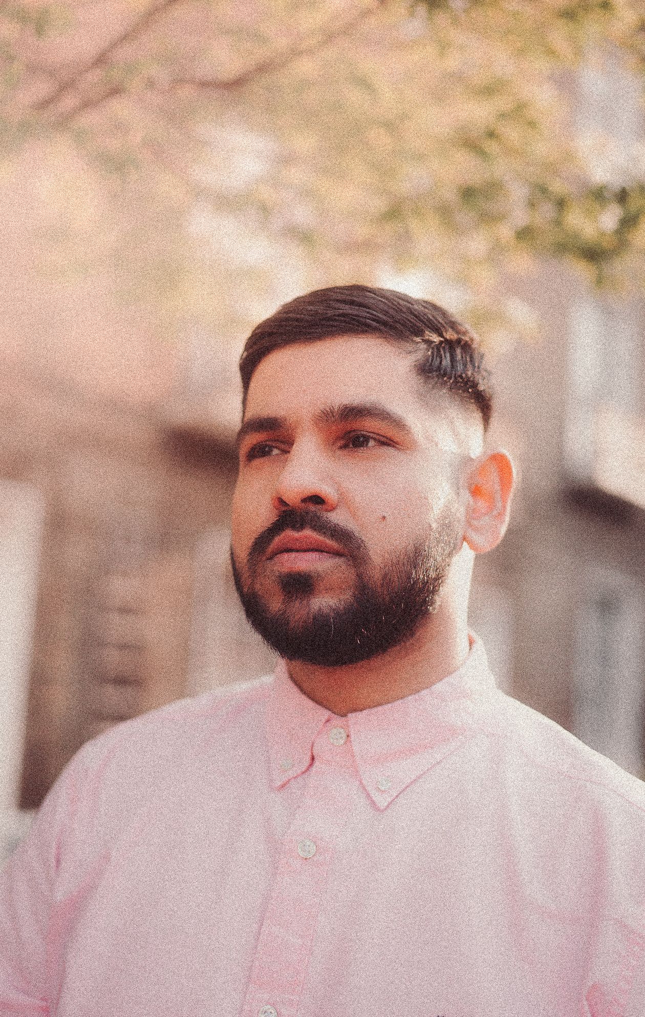 Portrait of person wearing a light pink button-up shirt against a soft-focus background.