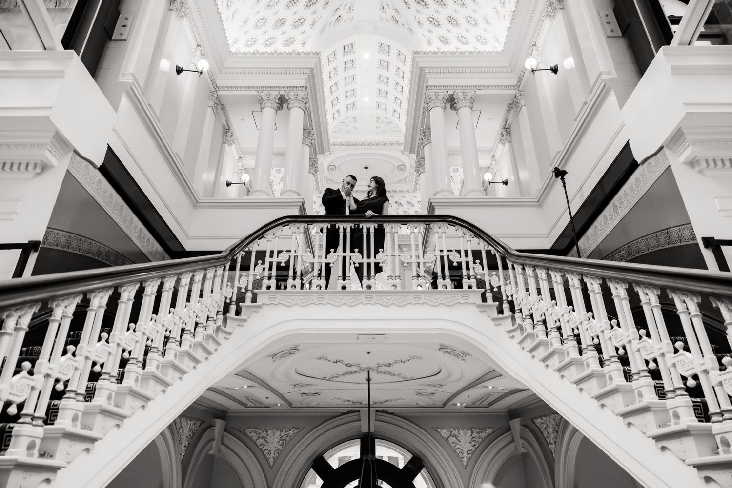 Grand ornate staircase with symmetrical marble steps and elegant architectural details in black and white.