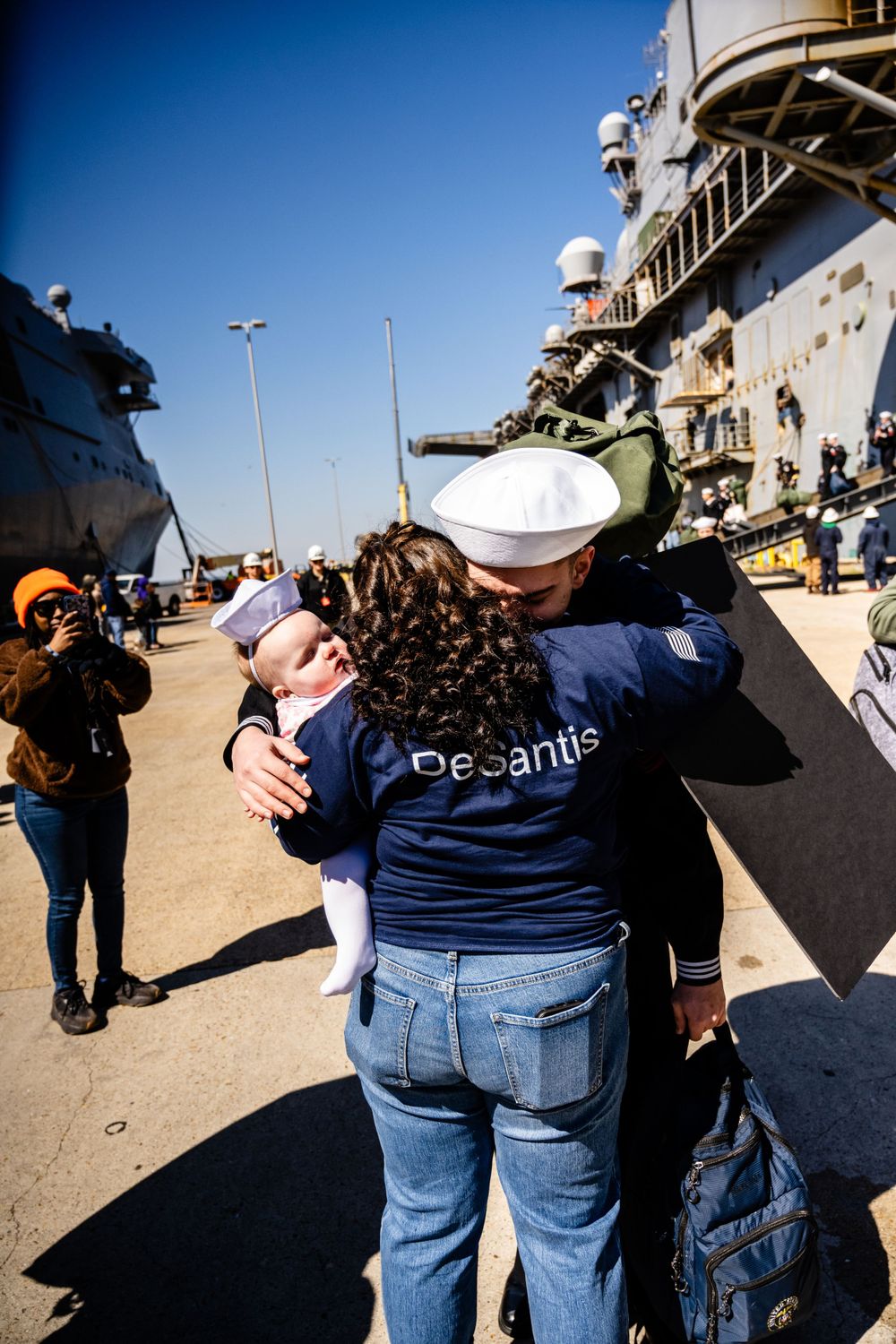 Emotional reunion embraces on ship deck during military homecoming.