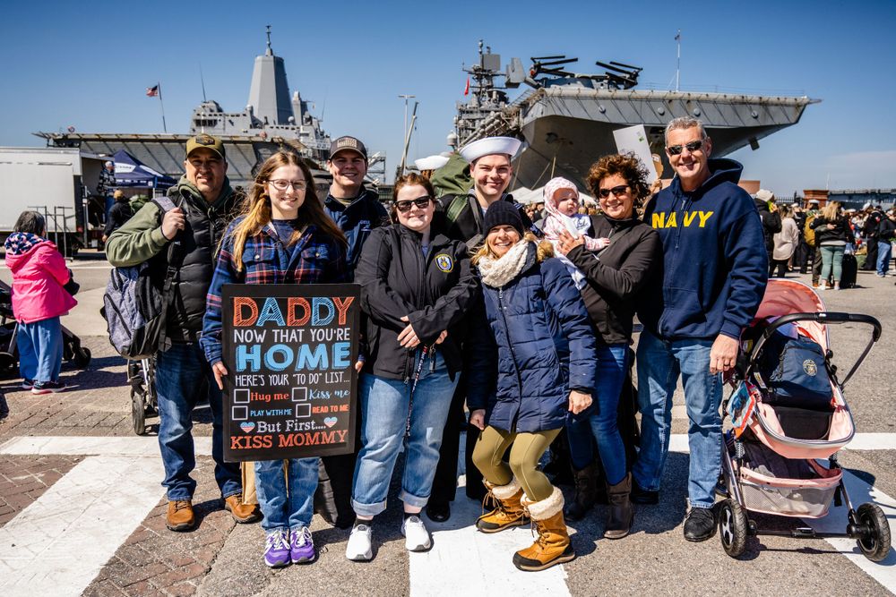 Family and supporters gather on a naval base dock to welcome home returning service members.