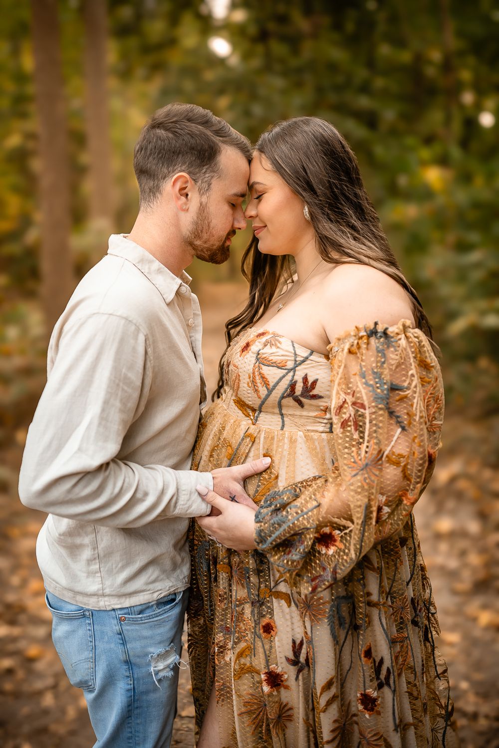 An intimate portrait of a couple sharing a tender moment in an autumn forest setting.