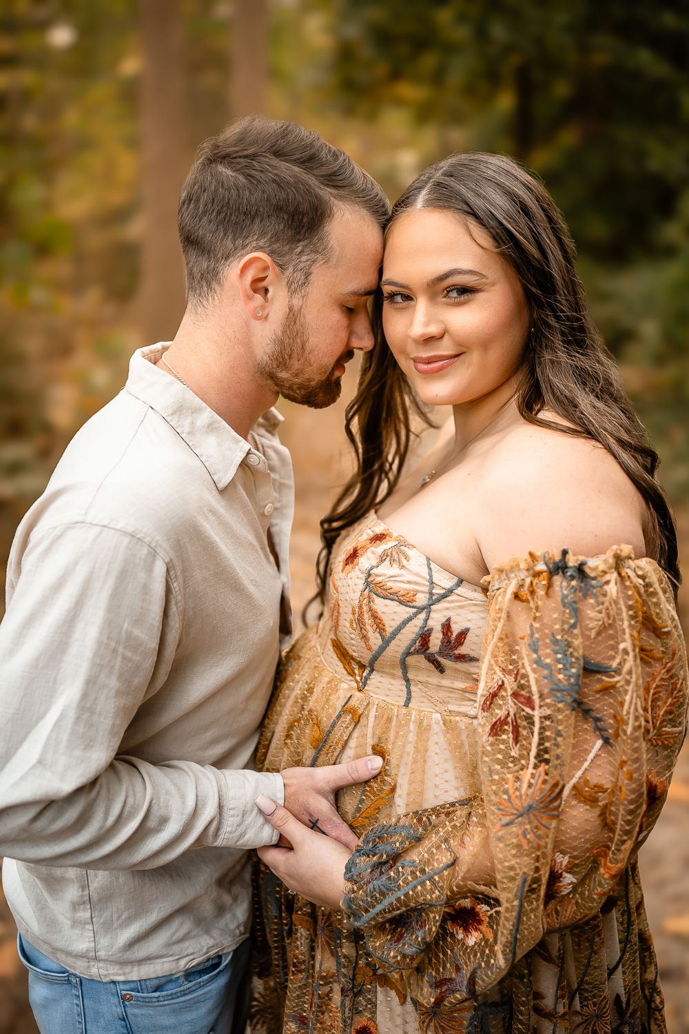 A romantic portrait capturing an intimate moment between a couple in autumn woodland.