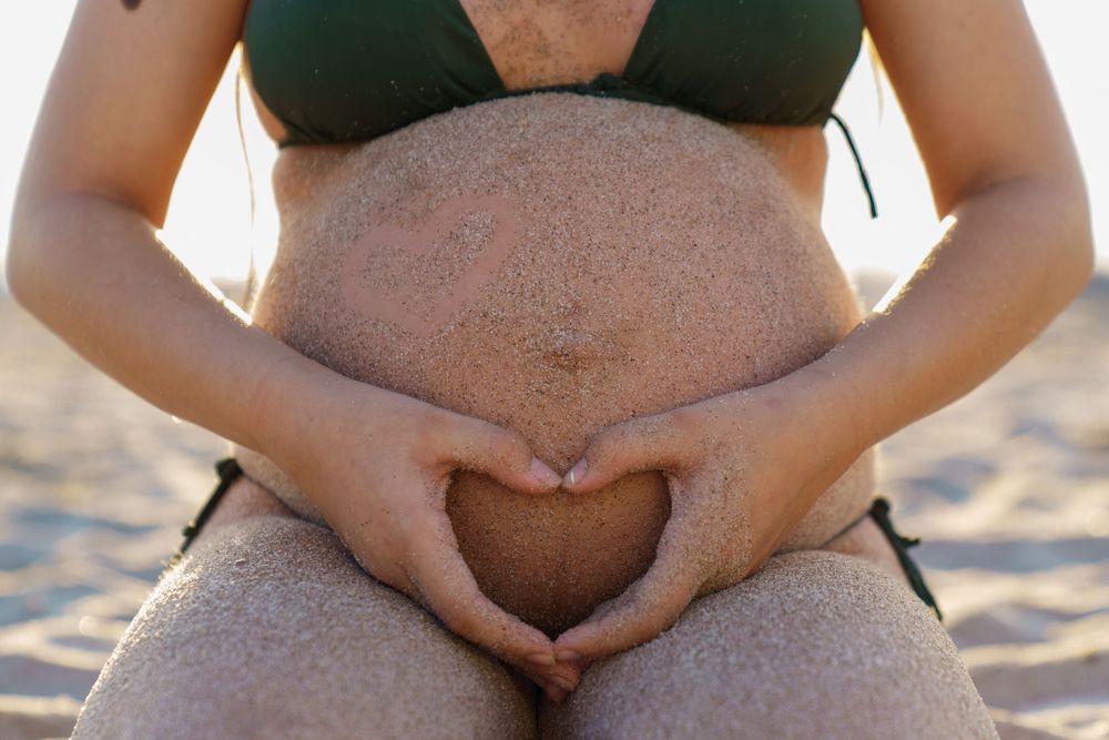 Pregnant mom in a bathing suit on the shoreline at sunrise, relaxed beach maternity portrait by SRX Media Group.