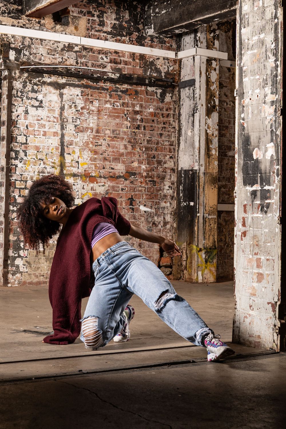 performance photography Brighton photo of a dancer in an abandoned building wearing jeans and a red jumper. stone wall in the background