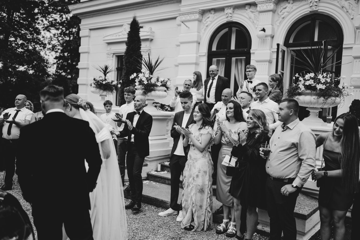 Black and white photo of wedding guests celebrating at an outdoor reception.